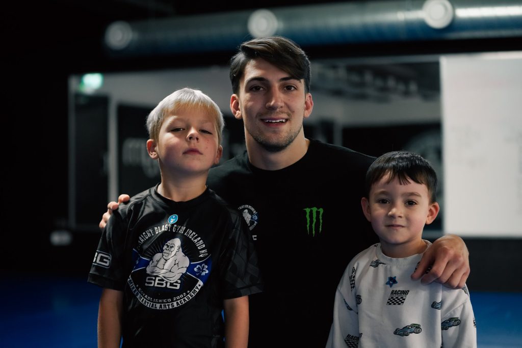 SBG coach smiling with two young students at SBG Ireland HQ